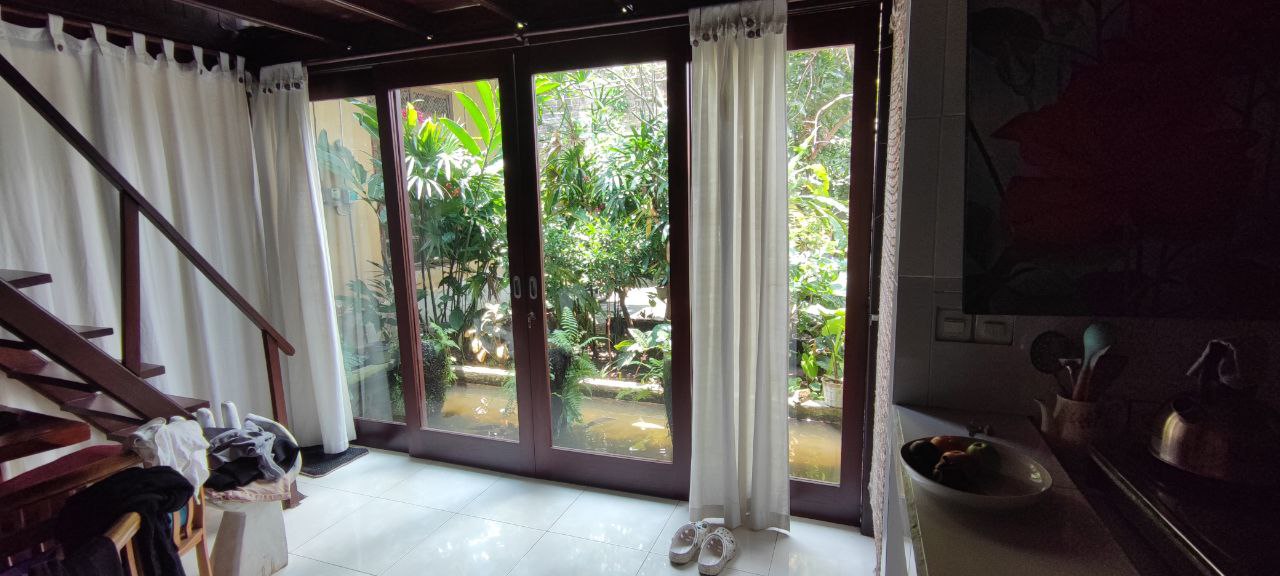 Large windows and tropical greenery beside the house