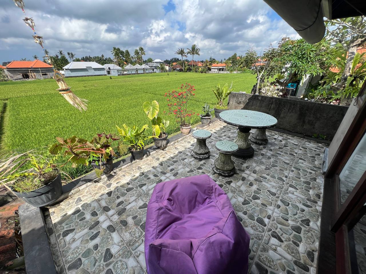 An open terrace with a beanbag and a table beside the rice field